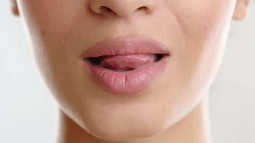 Lower Half of Female Face Woman Running the Tongue Along the Lower Row of Teeth