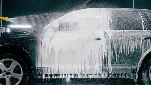 Close-up of car wash detergent dripping off a luxury car during a car cleaning or car wash