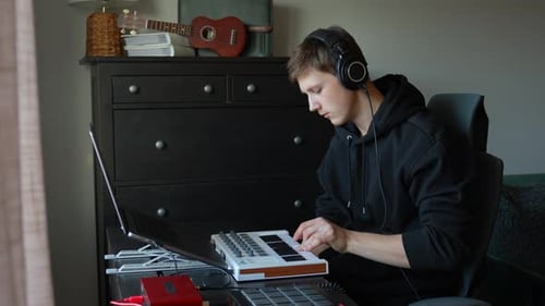 Young Man Composing Music at Home on Keyboard