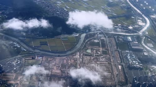 A cityscape covered by clouds with roads and buildings visible through the mist, aerial view