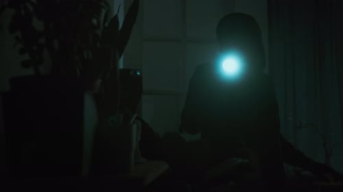 Two Silhouettes in a Dark Interior with Flashlight