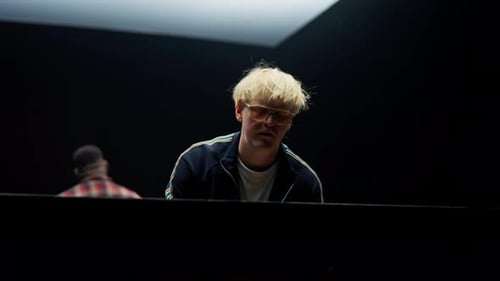 Blonde Haired Person Playing Piano in Dark Room