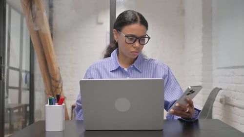 Adult at Desk Working on Computer and Using Phone