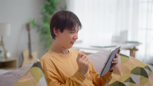 Smiling Man Using Tablet on Couch at Home