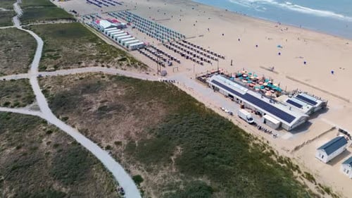 A beautiful aerial view of a sandy beach with rows of beach huts, people relaxing by the shore