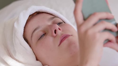 Woman Relaxing with Phone After Spa Treatment