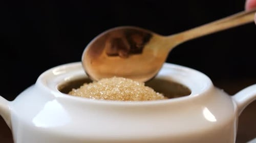 Close-up scooping brown sugar with spoon from bowl