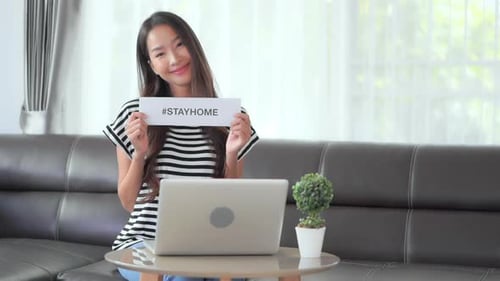 Woman Holds a Stay Home Sign Behind Laptop