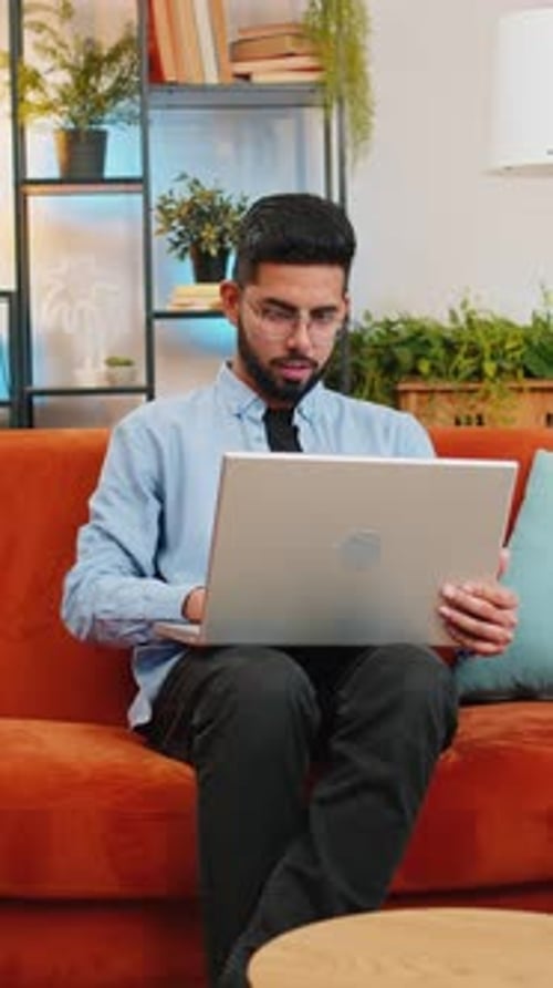 Man Sitting on Sofa Working on Laptop