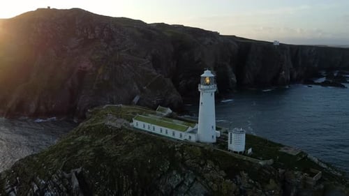 South Stack lighthouse aerial view circling island landmark to reveal golden sunrise