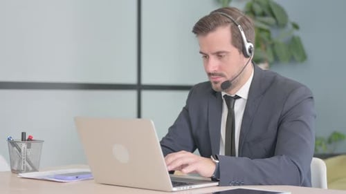 Businessman with Headset Working on Laptop