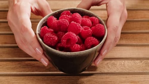 Bowl of Ripe Raspberries Displayed on Wood Surface