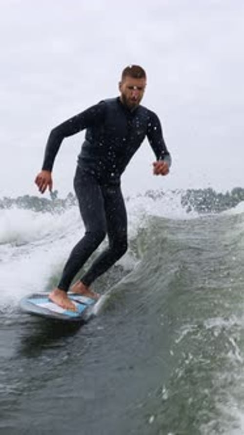 Man wake surfing on a wave in wetsuit