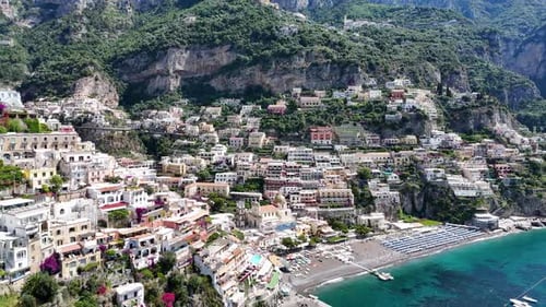 Dévoilement aérien lent de la plage de Positano entourée de hautes montagnes, d'une végétation luxuriante et d'une eau turquoise