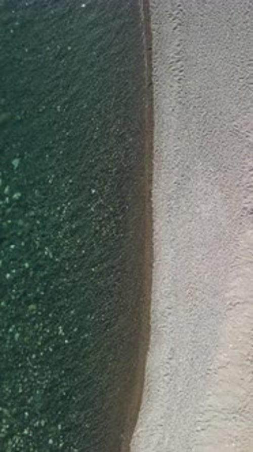 Vertical Aerial View on Calm Azure Sea and Volcanic Rocky Shores Small Waves on Water Surface in