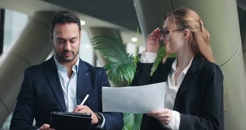Two Professional Colleagues Discussing a Document in an Office