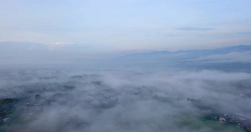 Drone footage over city with sea of mist above it