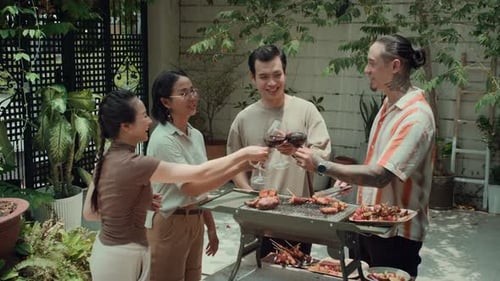 Four friends grilling and drinking wine together