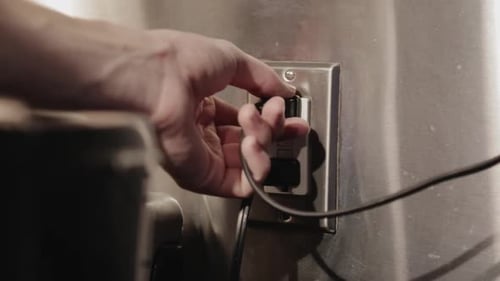 Pulling Out The Electrical Cord From The Outlet To Unplug The Appliance - Close Up Shot