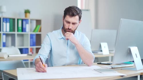 young creative designer or architect working in the office at work at a computer desk with drawings.