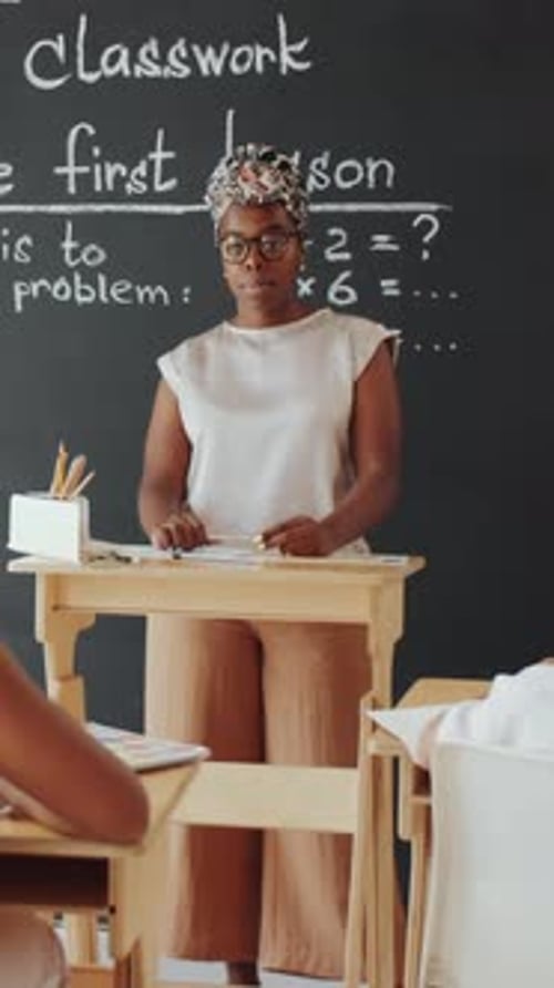 African American Female Teacher Explaining Math Equations to Students in School