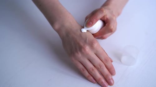 Frau reibt Creme auf ihre Hände, Nahaufnahme auf weißem Hintergrund