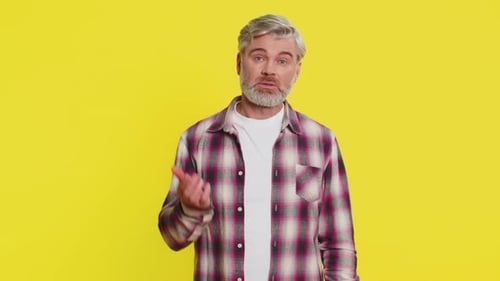 Man Talking and Removing Glasses on Yellow Background