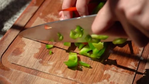 Chopping Red And Green Bell Peppers In Dice On Chopping Board. - close up