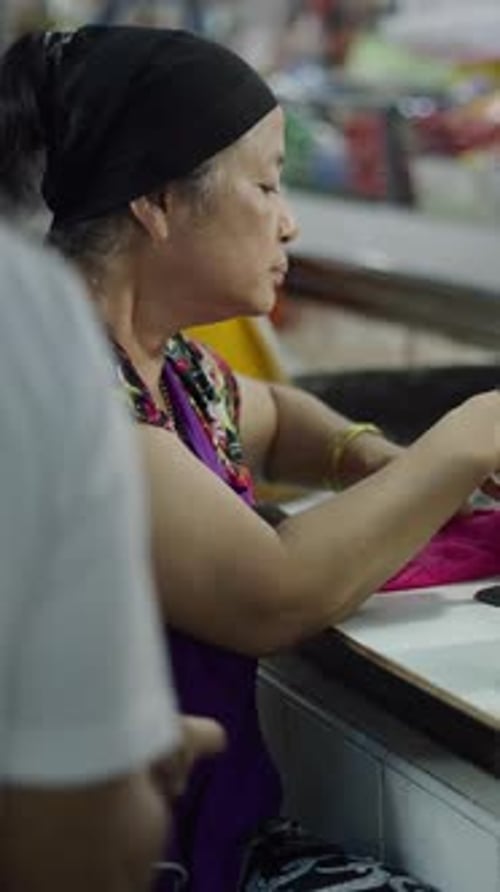 Vendedor asiático de peixe cozido recebe dinheiro de um cliente após entregar seu pedido de peixe