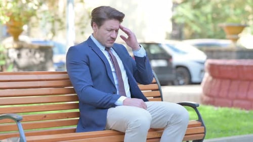 Tired Businessman Sitting Outdoor with Headache