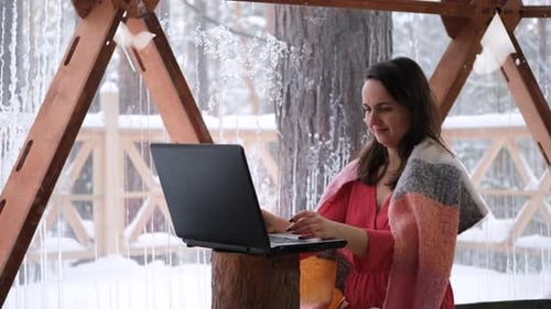 Woman Working on Laptop in Snowy Outdoor Enclosure