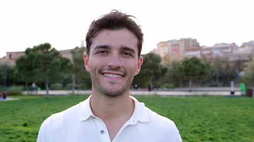 Retrato externo de jovem homem bonito sorridente olhando para a câmera no parque da cidade