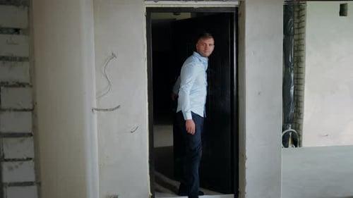 Hombre seguro de Wide Shot abriendo la puerta que entra a un nuevo apartamento en reparación mirando