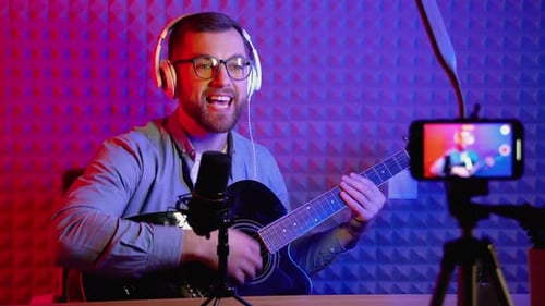 Young Adult Playing Guitar into Microphone