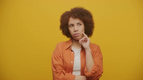 Woman Thinking with Hand on Chin on Yellow