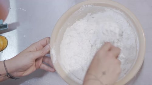 Hands Mixing Dough in a Bowl