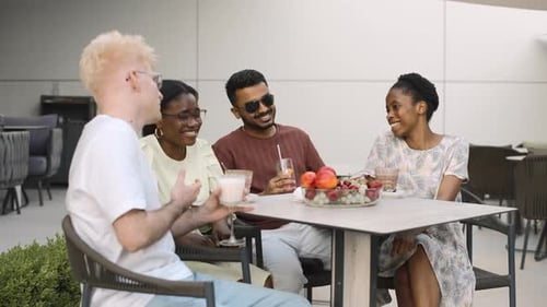 Four friends, representing diverse ethnicities, relax and enjoy conversation at a cafe table