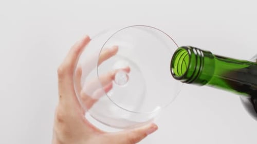 Hands of caucasian woman pouring white wine into glass with copy space