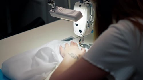 Close Up in the Sewing Workshop Young Girl Works with a Sewing Machine and White Fabric