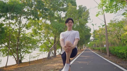 Asian young sportsman stretching body warm up while exercise in park.