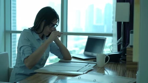Elegant businesswoman working at desk making notes on cellphone in city office