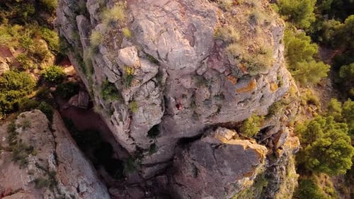 Climbing woman rapel down the mountain from the top. Drone view of girl rappeling descending rock