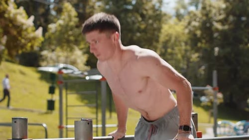 Athletic Caucasian Shirtless Man Practicing Dips on Parallel Bars Training Triceps on Playground