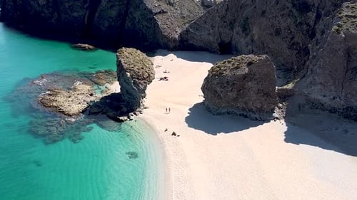 Seashore coastline drone aerial view of people at unspoiled beach in Almeria, Playa de los Muertos