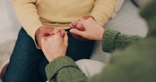 Couple, love and holding hands for empathy and support or security on home sofa