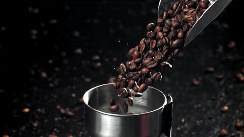 Die Kaffeebohnen fallen in die funktionierende Mühle, gefilmt mit einer Hochgeschwindigkeitskamera mit 1000 Bildern pro Sekunde