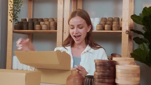 A young pretty woman entrepreneur checking and packaging craft products