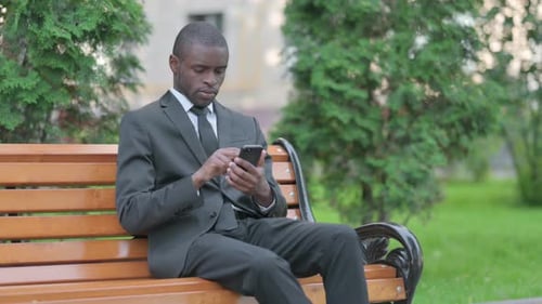 Man on Park Bench Uses Smartphone