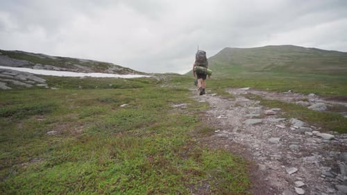 Tourist Carrying A Huge Hiking Backpack Walking With His Dog At Trekanten Mountain Trail In Norway.