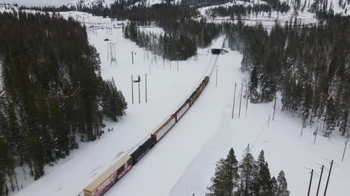 4K Drone Follow Shot of Train in Snowy Mountains